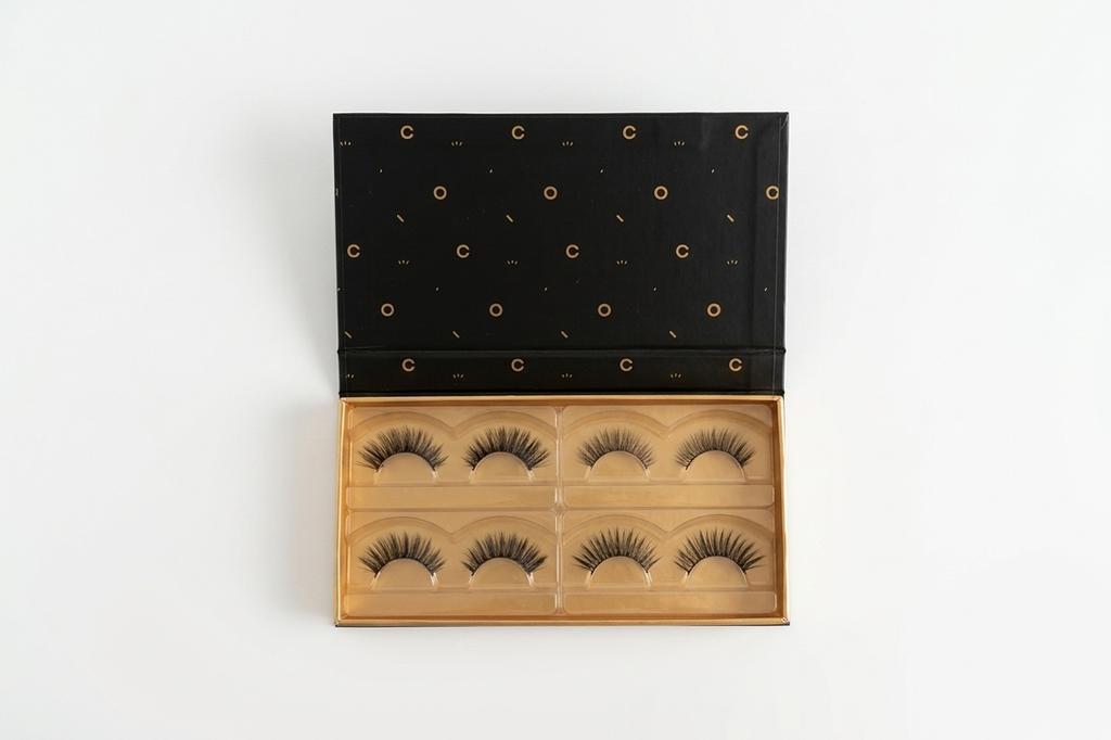 Set of false eyelashes in a wooden display case with a black lid on a white background