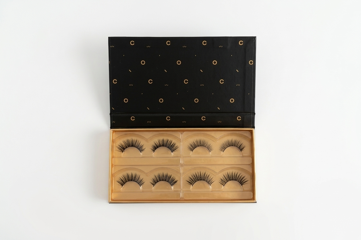 Set of false eyelashes in a wooden display case with a black lid on a white background