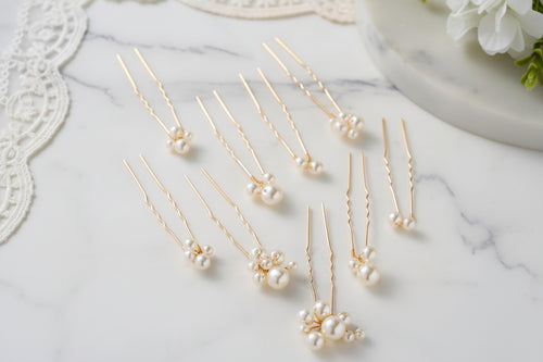 Gold hairpins with pearls on a marble surface