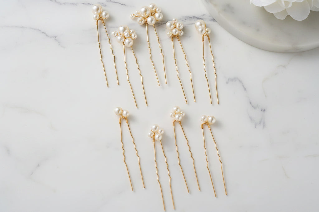 Gold hairpins with pearls on a marble surface