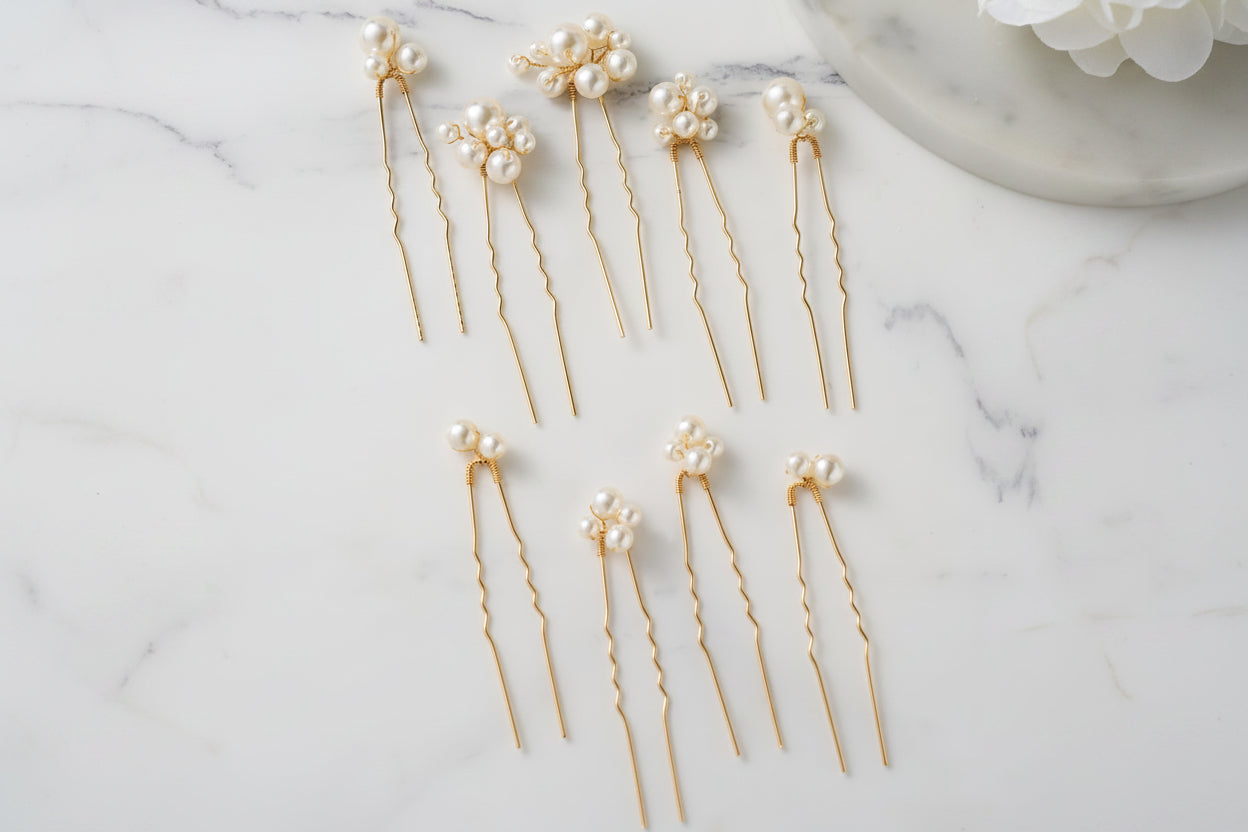 Gold hairpins with pearls on a marble surface