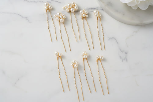 Gold hairpins with pearls on a marble surface