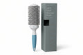 Hairbrush with blue handle and white bristle head next to its packaging on a white background