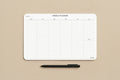 A white weekly planner pad with a black pen on a textured beige background. The planner features columns for Monday through Sunday and is branded with 'Clever Signs' in the bottom right corner.