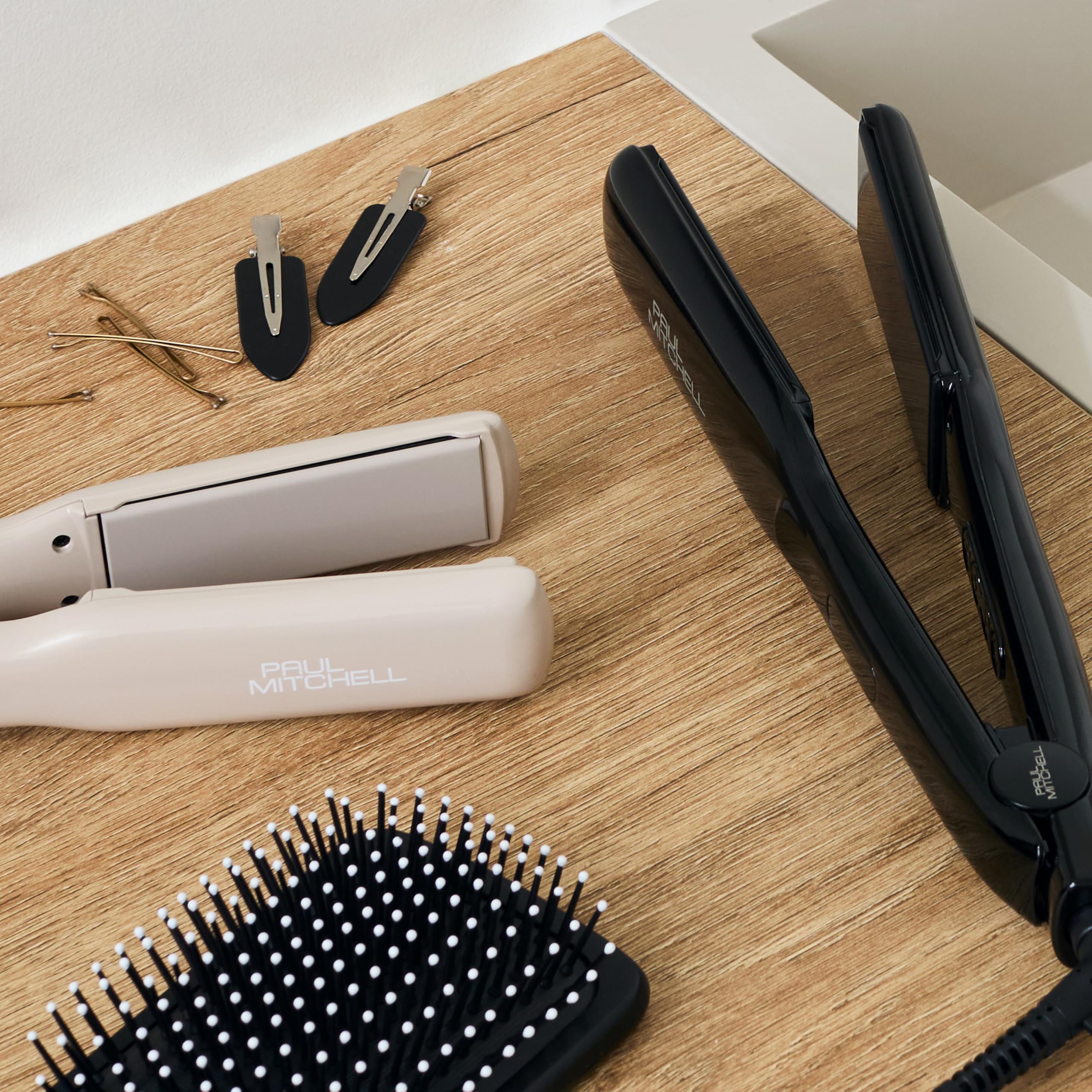 Hair straightener, hairbrush, and hair clips on a wooden surface