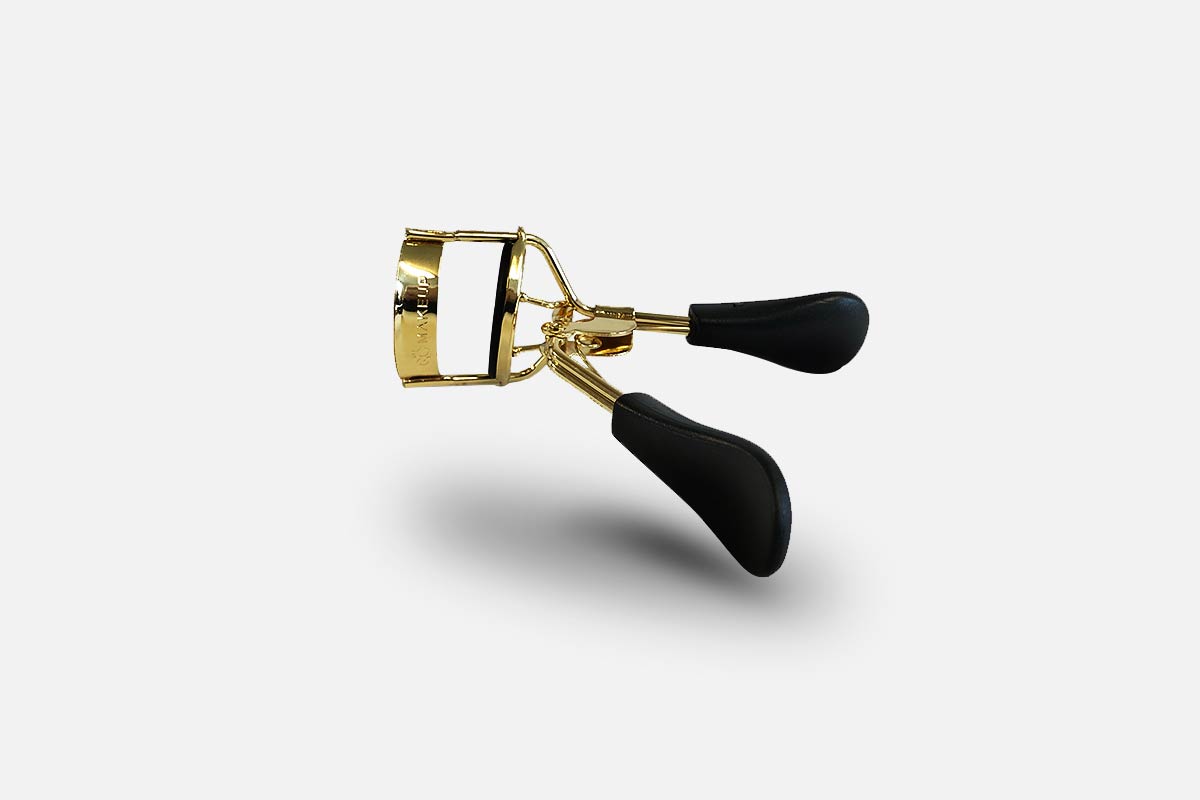 Eyelash curler with gold and black design on a white background