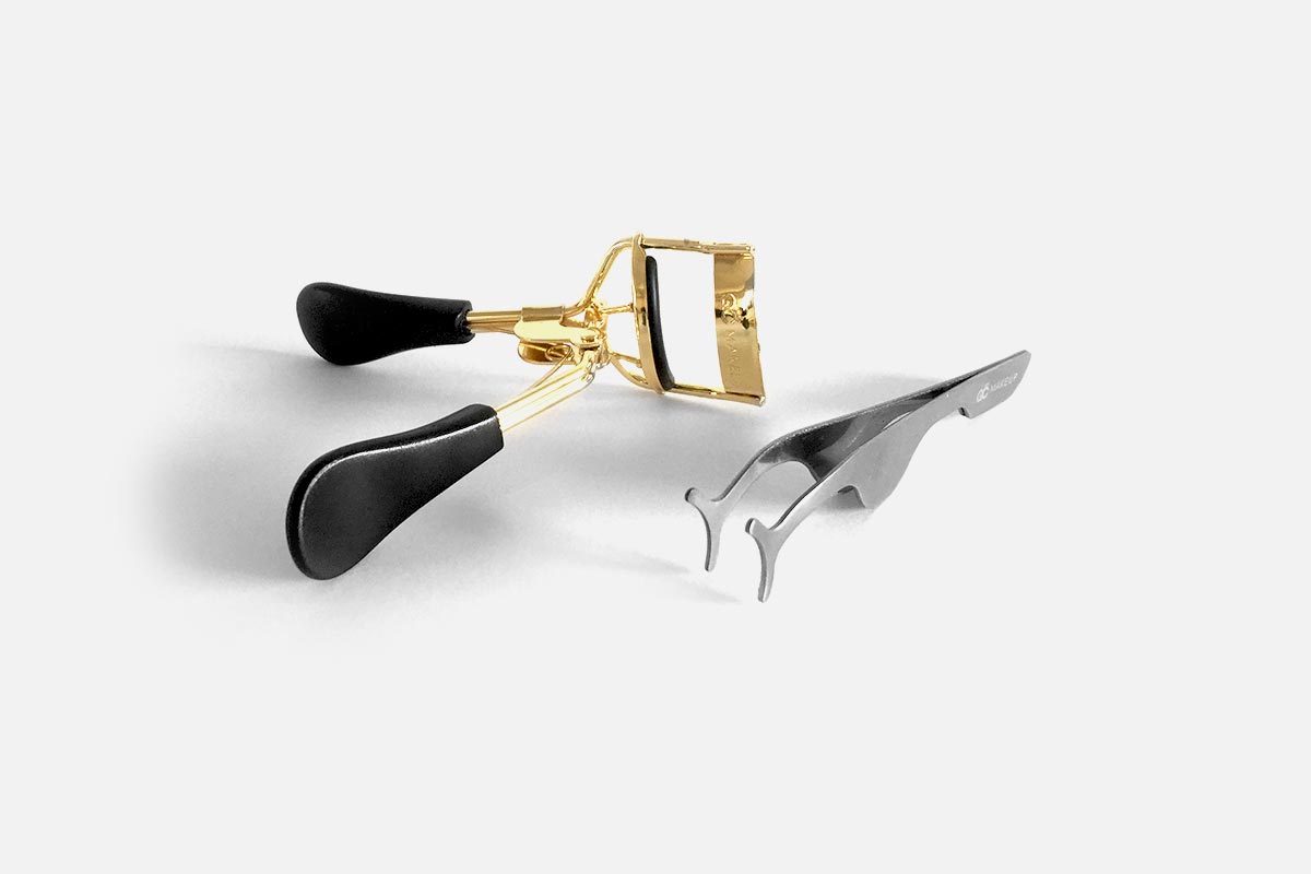 Eyelash curler with black and gold design on a white background