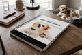 Open book on a wooden table with a dog in the background