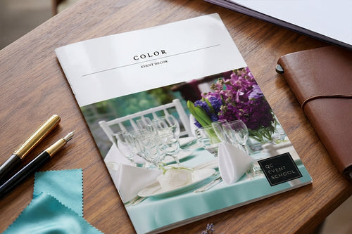Book titled 'Color Event Decor' on a wooden table with stationery items.