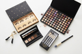 Makeup products including eyeshadow palettes, eyelashes, and brushes on a white background