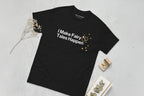 Black t-shirt with 'I Make Fairy Tales Happen' text on a light gray surface.