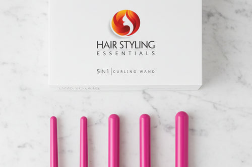 Hairstyling wand box with five hair styling barrel curler attachments on a marble surface. 