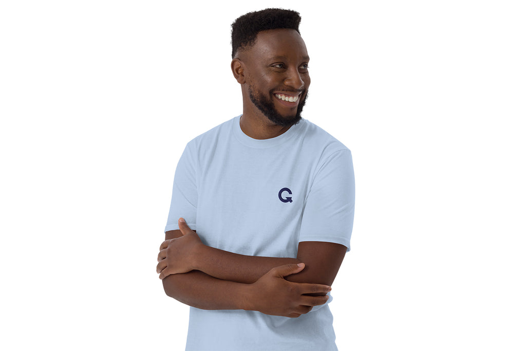 Man wearing a light blue t-shirt with a QC logo on a white background