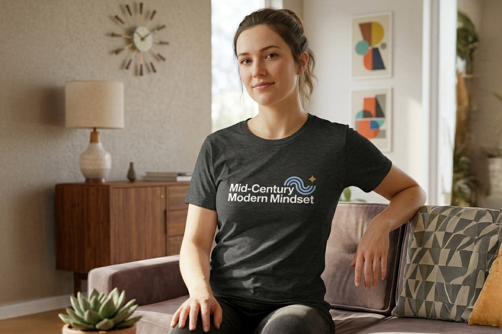 Woman wearing a 'Mid-Century Modern Mindset' t-shirt sitting on a couch in a living room.