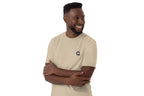 Man wearing a beige t-shirt with a QC logo on a white background