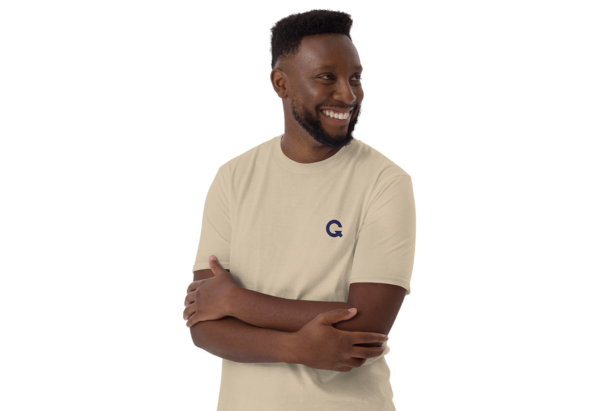 Man wearing a beige t-shirt with a QC logo on a white background