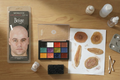 Makeup palette, bald cap, stipple sponge and fake wounds on a work table
