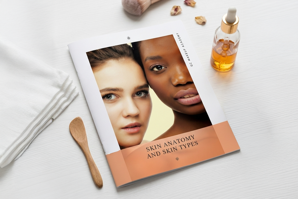 Book titled 'Skin Anatomy and Skin Types' with two faces on the cover, placed on a white surface with a bottle of oil and wooden spatula.