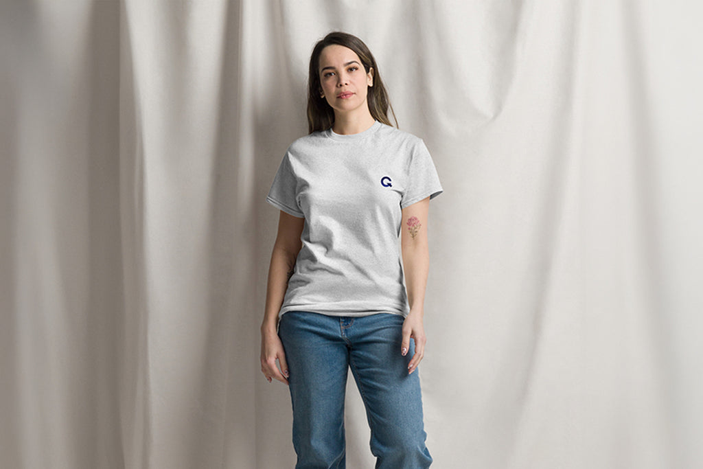 Person wearing a gray t-shirt with a Q logo on a plain background