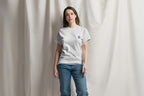 Person wearing a gray t-shirt with a Q logo on a plain background