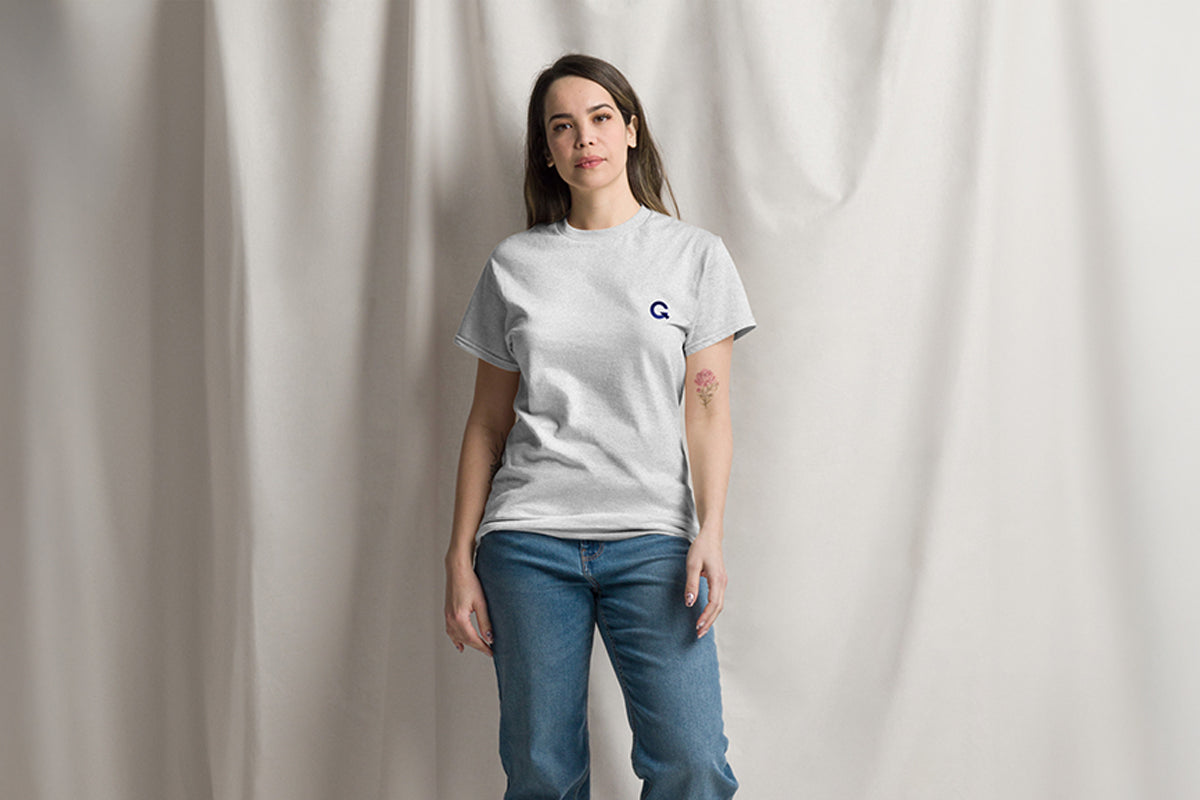 Person wearing a gray t-shirt with a Q logo on a plain background