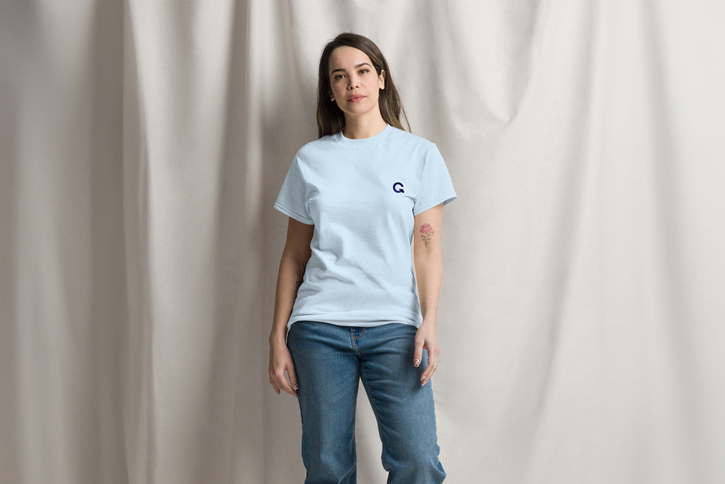 Woman wearing a light blue t-shirt with a Q logo on a plain background