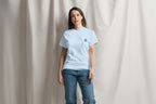 Woman wearing a light blue t-shirt with a Q logo on a plain background