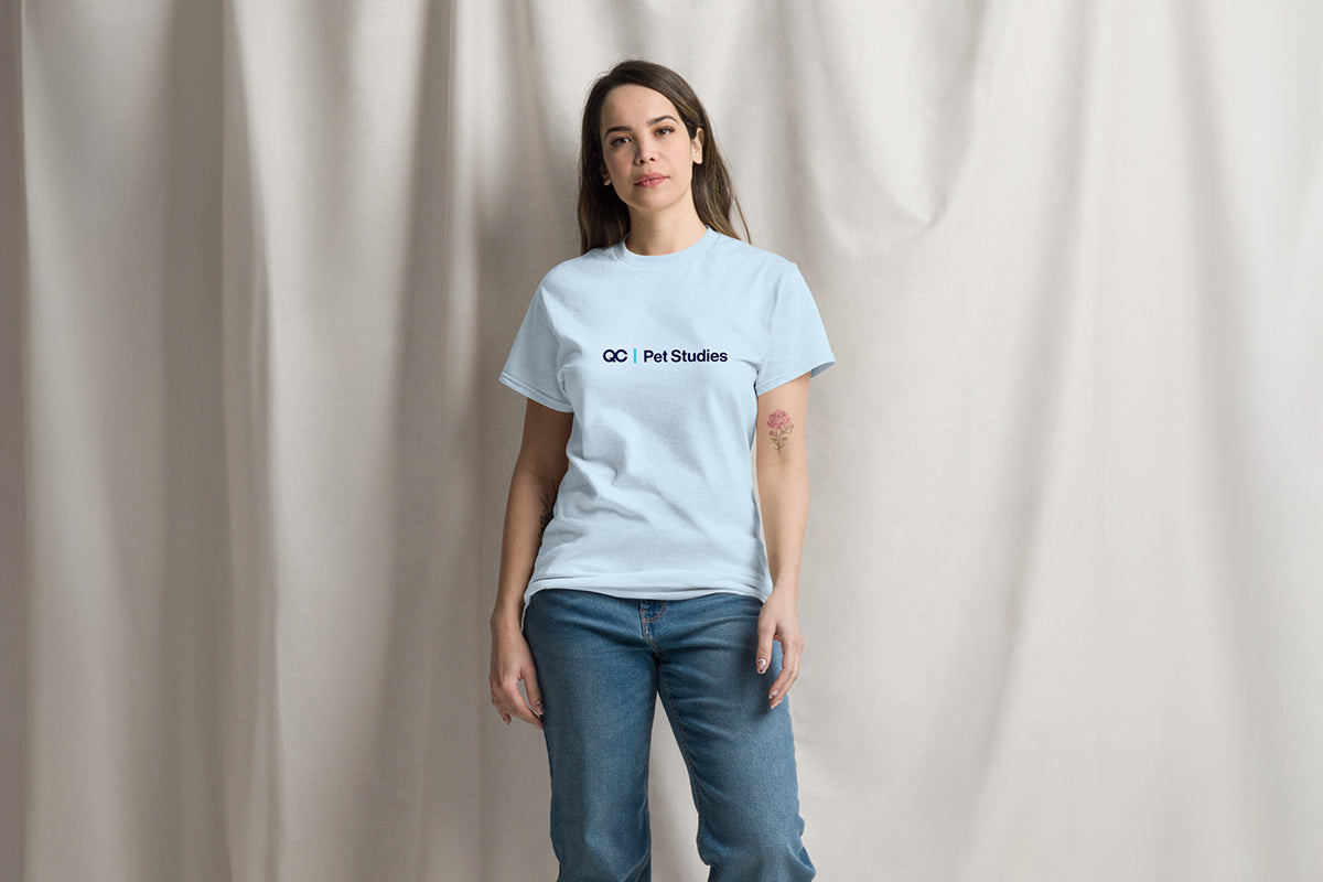 Person wearing a light blue t-shirt with QC Pet Studies logo on a plain background