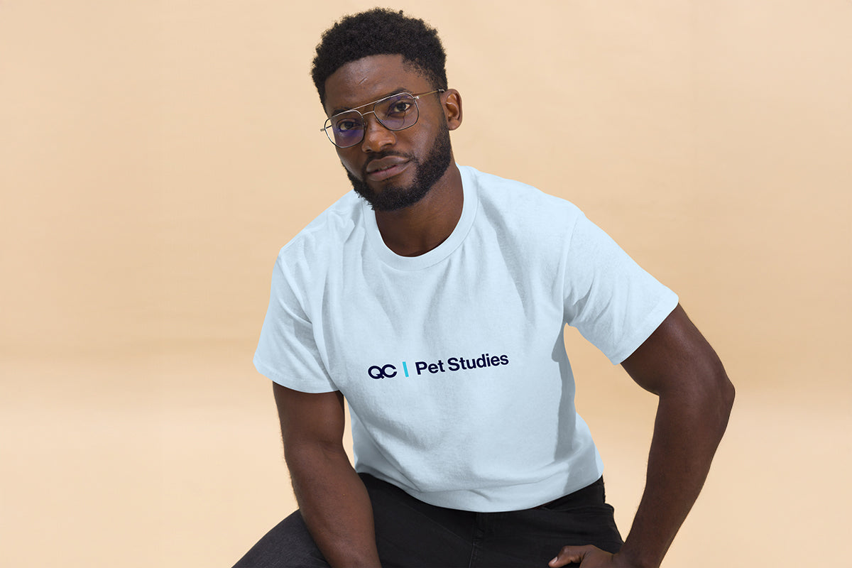 Man wearing a light blue t-shirt with 'QC Pet Studies' text on a beige background