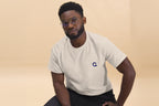 Man wearing a beige t-shirt with a Q logo on a beige background