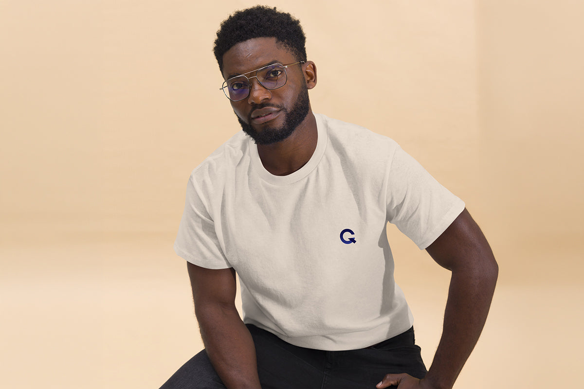 Man wearing a beige t-shirt with a Q logo on a beige background