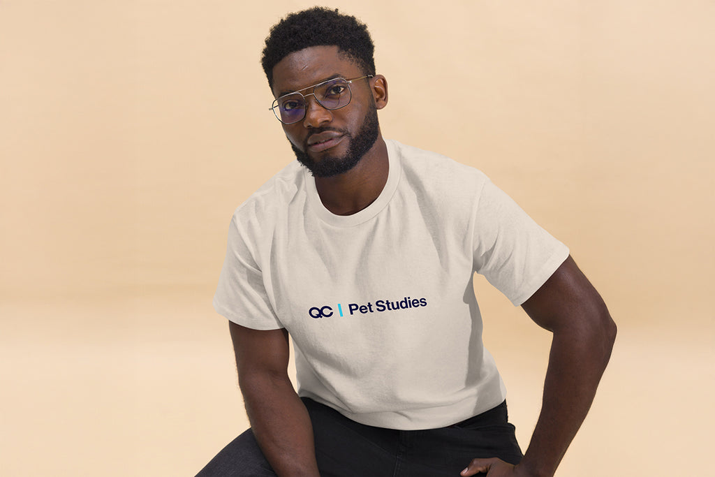 Man wearing a white t-shirt with a QC Pet Studies logo on a beige background