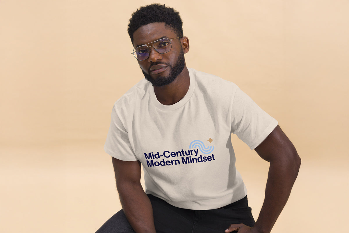 Person wearing a beige t-shirt with 'Mid-Century Modern Mindset' text on a beige background