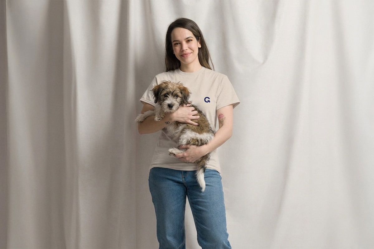 Woman holding a small dog in front of a plain background