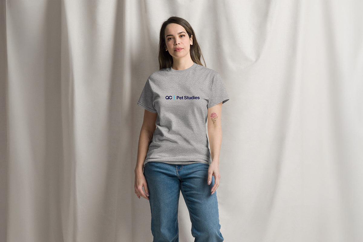 Person wearing a gray t-shirt with a QC Pet Studies logo against a plain background