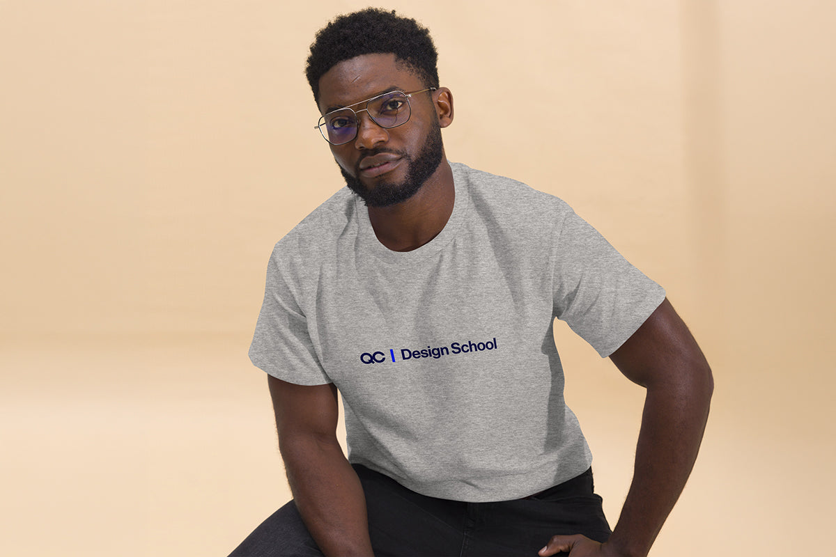 Man wearing a gray t-shirt with 'QC Design School' logo on a beige background