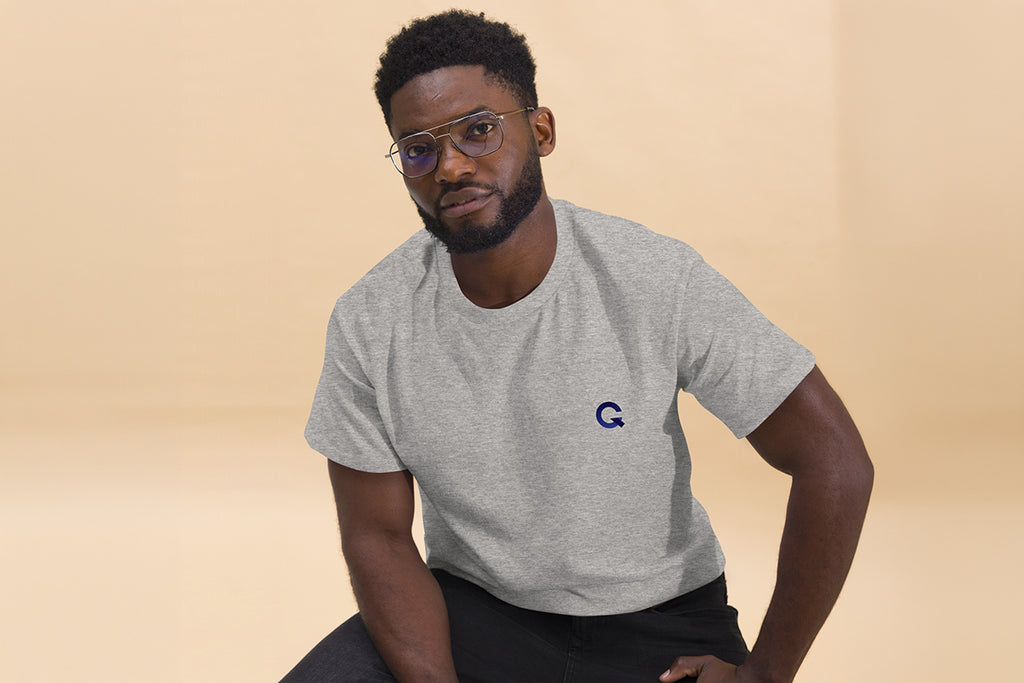 Man wearing a gray t-shirt with a Q logo on a beige background