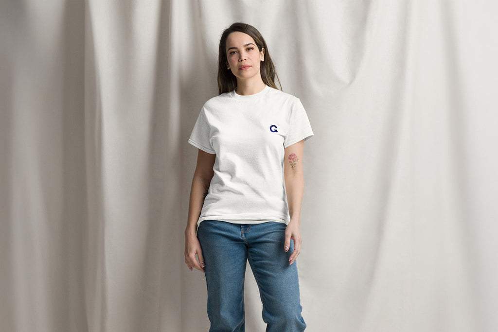 Person wearing a white t-shirt with a Q logo on a plain background