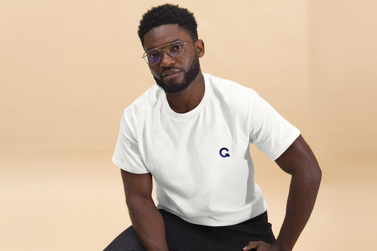 Man wearing a white t-shirt with a QC Design School logo on a beige background