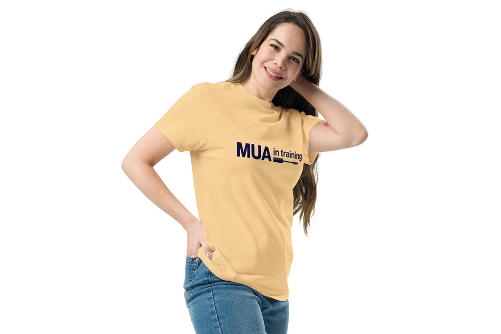 Woman wearing a yellow t-shirt with 'MUA in training' text on a white background