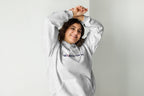 Person wearing a gray hoodie with a QC Makeup Academy logo on a plain background