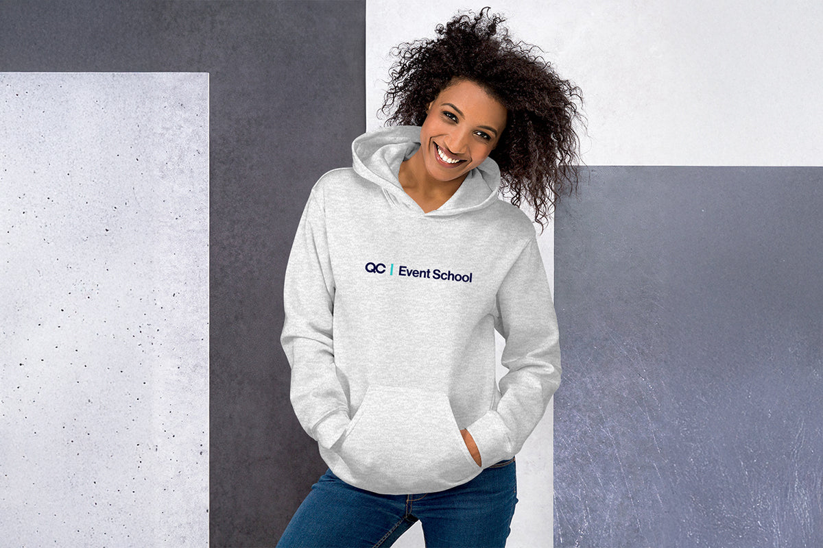 Woman wearing a gray hoodie with 'QC Event School' logo against a gray wall.