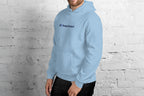 Person wearing a light blue hoodie with 'QC Design School' text against a white brick wall.