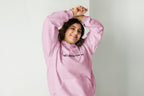 Person wearing a pink hoodie with a QC Makeup Academy logo on a plain background
