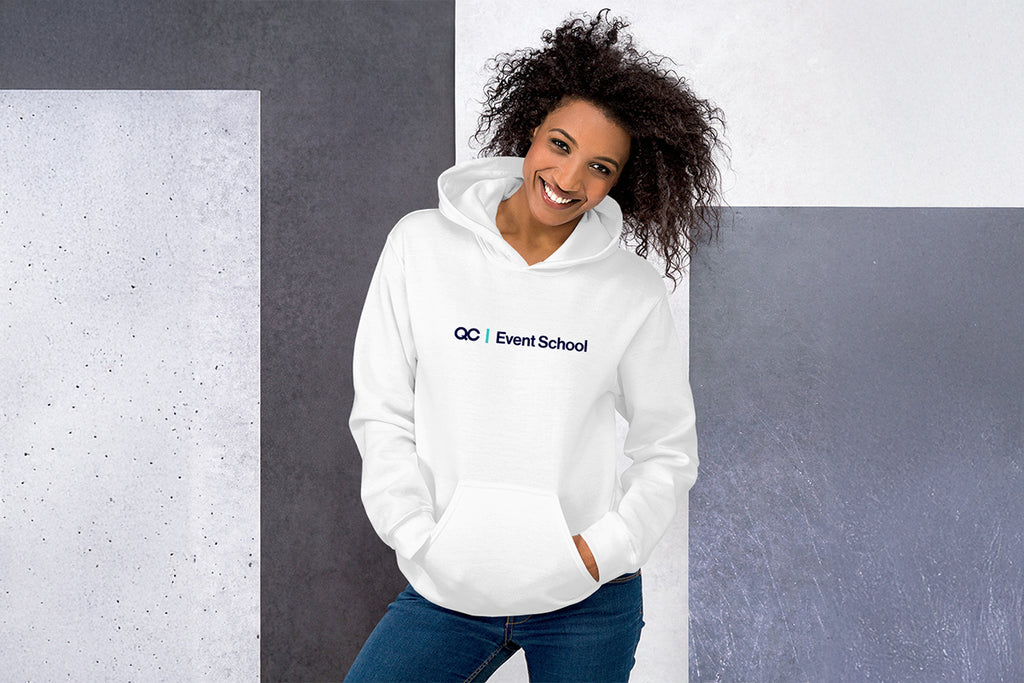 Woman wearing a white hoodie with 'QC Event School' logo against a gray wall.