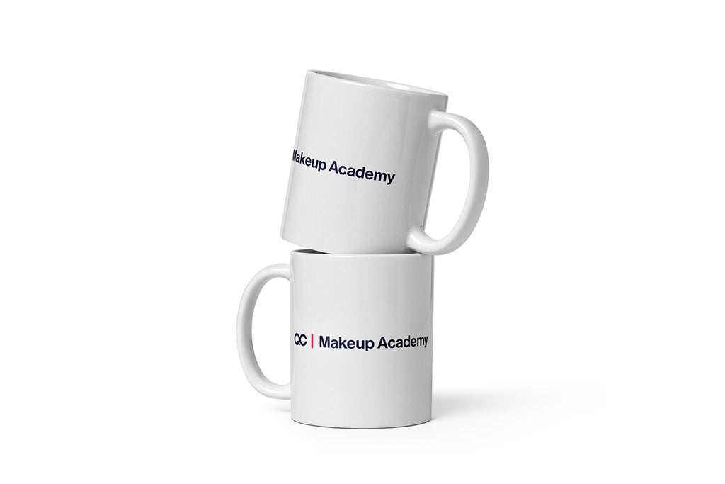 Two white mugs with 'QC Makeup Academy' text on a white background