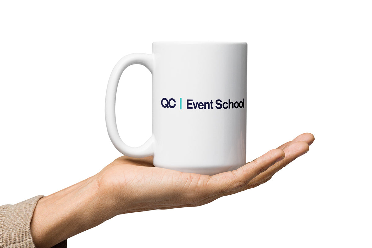 White mug with 'QC Event School' logo held in a hand on a white background