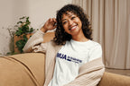 Woman wearing a off-white 'MUA in Training' shirt sitting on a couch.